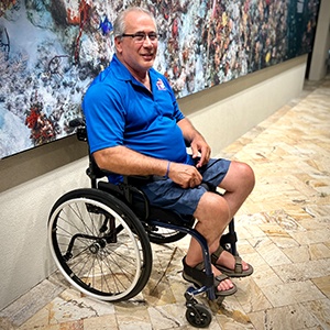 Todd in Mens Blue Polo sat in wheelchair on Cayman Brac
